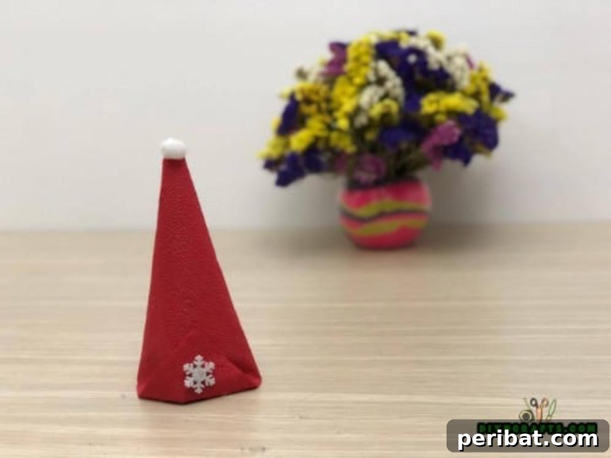 5 DIY Christmas Napkin Designs: Festive Folds, Easy Video How-To 37 Christmas Hat Napkin - Add snowflake embellishment for a cute, completed Christmas hat napkin.