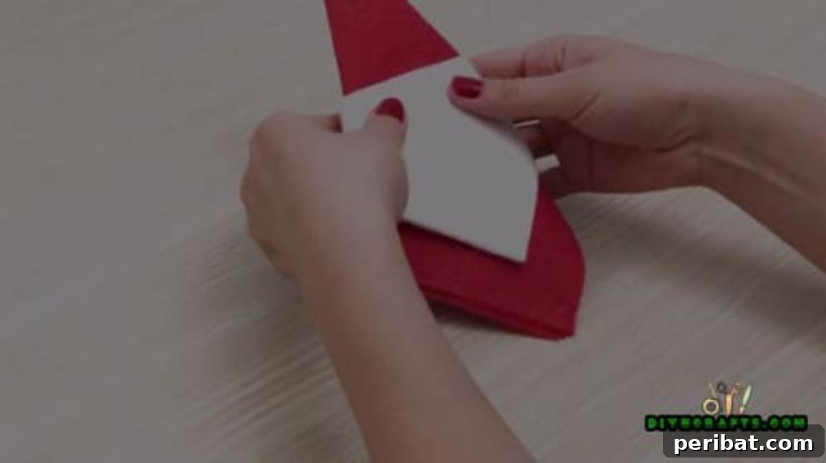 5 DIY Christmas Napkin Designs: Festive Folds, Easy Video How-To 5 Santa Napkin - Wrap white napkin around red to form Santa's hat and beard for your festive table.