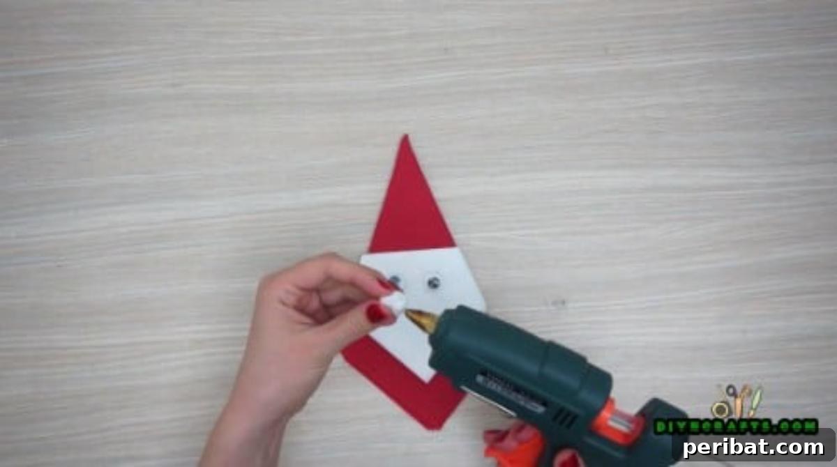 5 DIY Christmas Napkin Designs: Festive Folds, Easy Video How-To 7 Santa Napkin - Finish Santa's hat with a cotton ball for a festive touch on your napkin fold.
