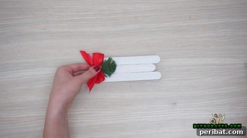 Effortless Holiday Crafting 5 DIY Ornament Videos 9 Embellish the craft stick sleigh with a bow and pine needles