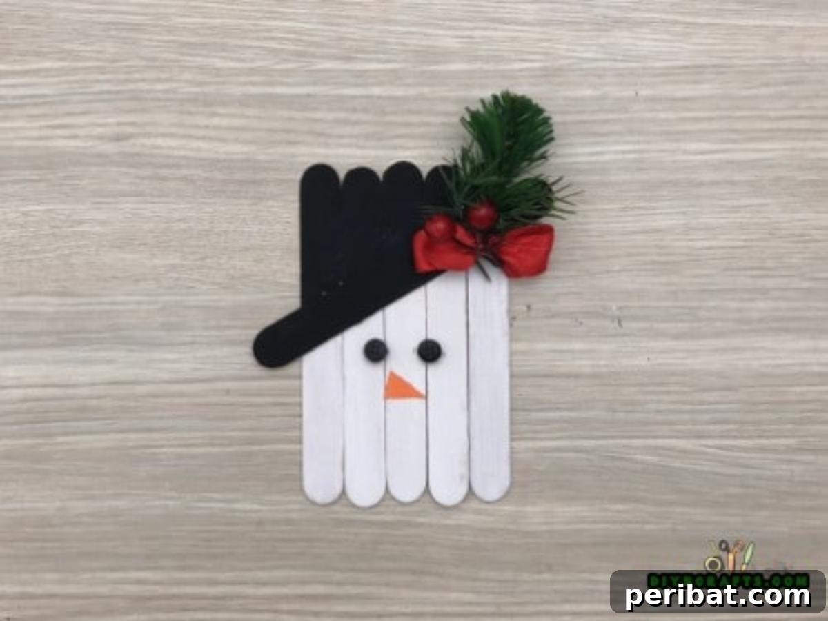 Minute-Made Snowmen: 5 Speedy & Creative Crafts 9 Finished craft stick snowman with a black hat, button eyes, and an orange paper carrot nose