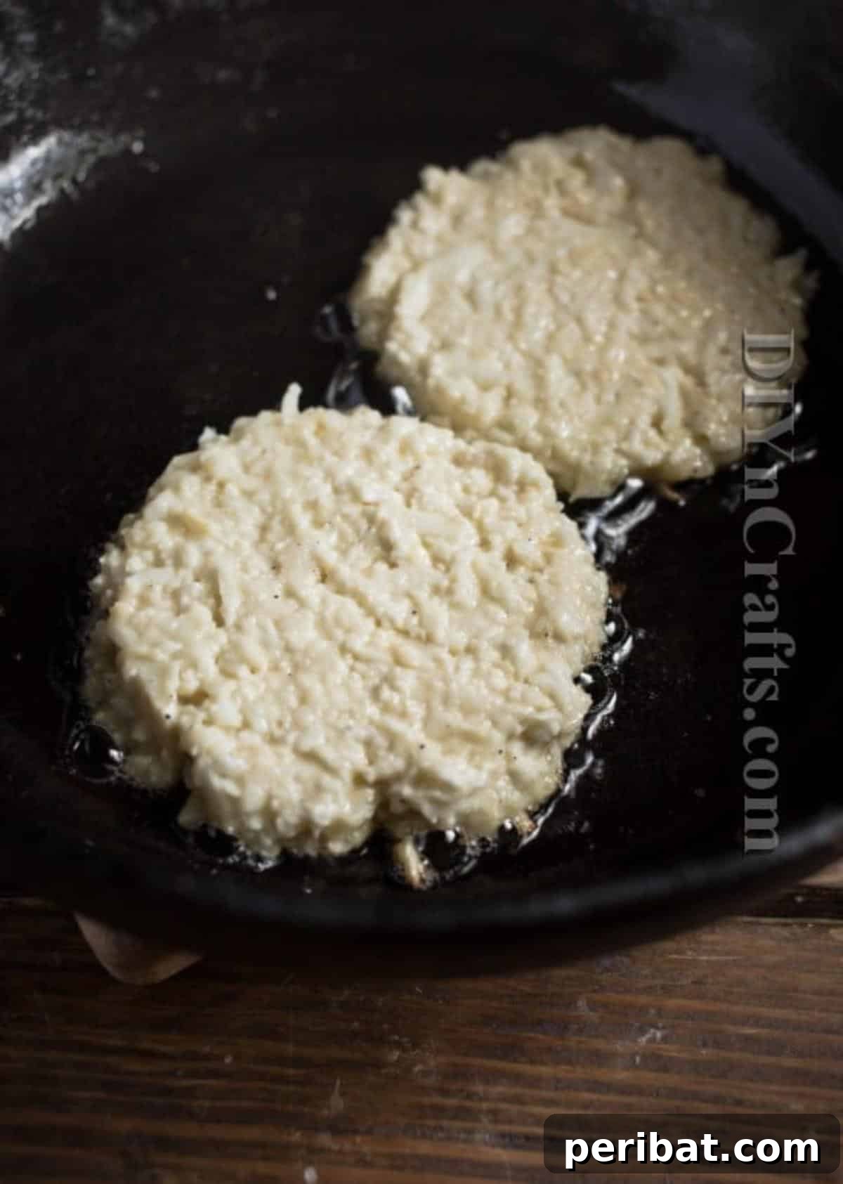 Cauliflower Fritters: The Guilt-Free Upgrade to a Beloved Classic 5 Cauliflower fritters sizzling in a hot pan, turning golden brown. Emphasizing the cooking process.