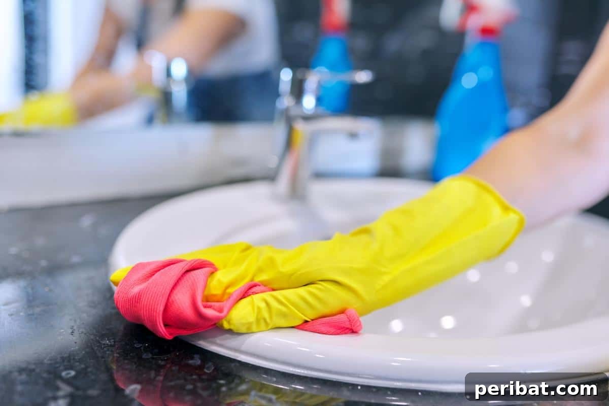 A hand wiping down a bathroom sink with a homemade, natural cleaning solution, demonstrating eco-friendly bathroom care.
