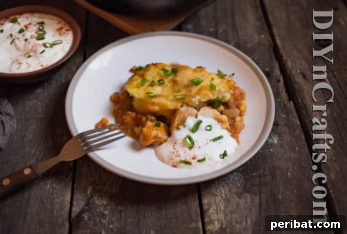 Serve topped with sour cream, cilantro, or your favorite salsa. A close-up of a slice of Chicken Tamale Pie on a plate, garnished with sour cream and fresh cilantro.