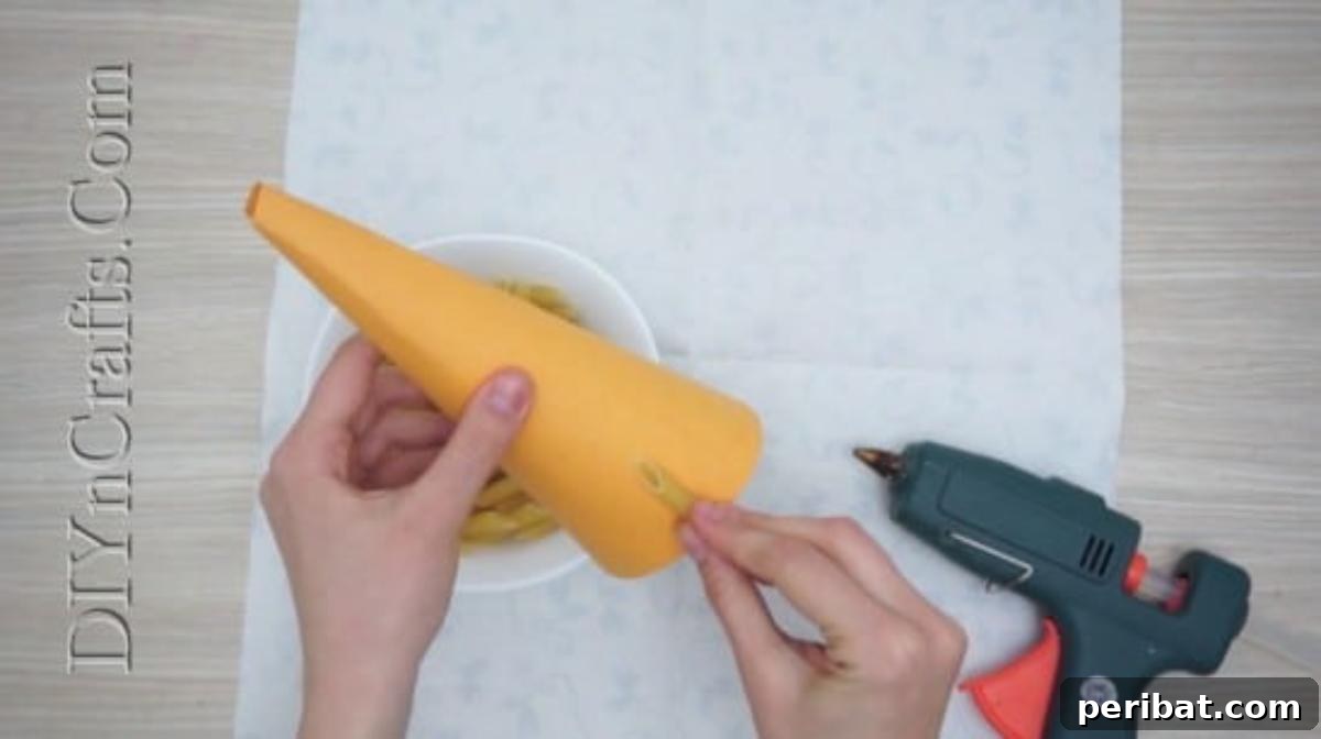 Pasta being carefully arranged and glued to cover the entire paper cone.