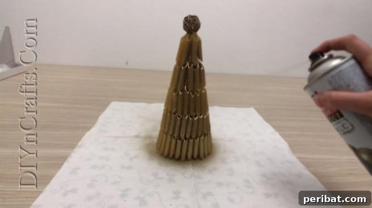 Applying metallic spray paint to the pasta-covered cone for a shimmering finish.