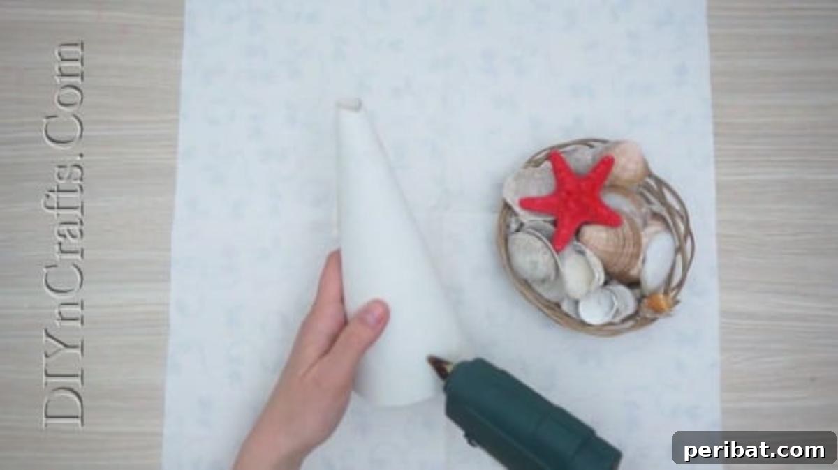 Hot gluing clam shells onto a paper cone, starting from the base.