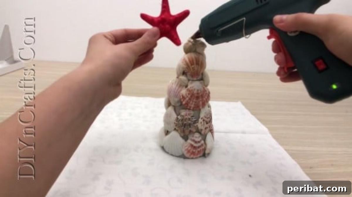 Attaching a starfish to the apex of the shell Christmas tree as a festive topper.