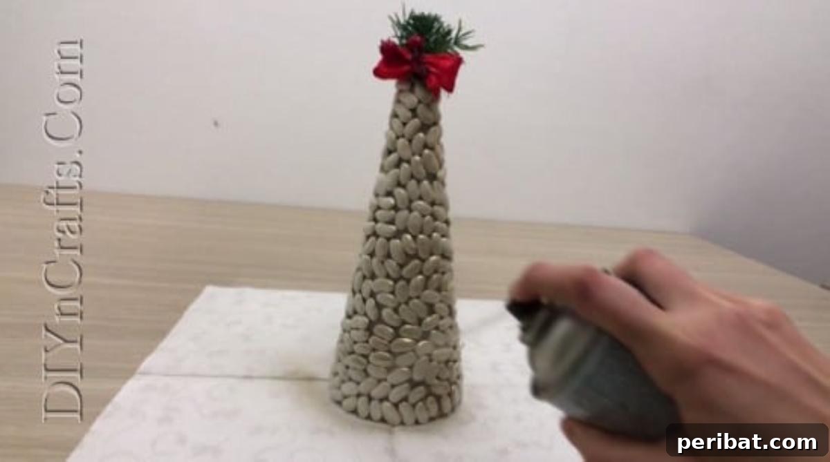 Spray painting the bean Christmas tree with metallic paint for a dazzling finish.