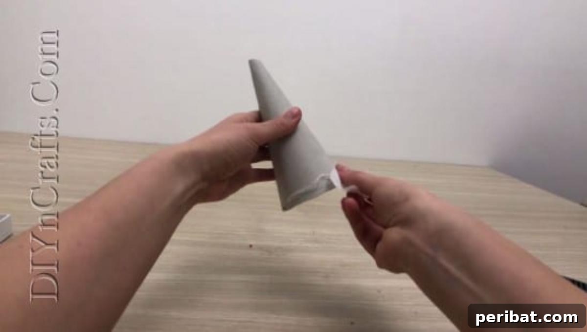 Faux flower petals being carefully layered and glued onto the paper cone.