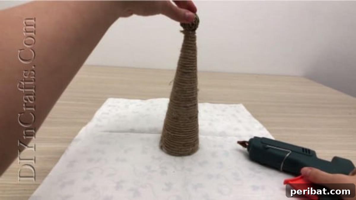 Finished twine Christmas tree decorated with small embellishments.
