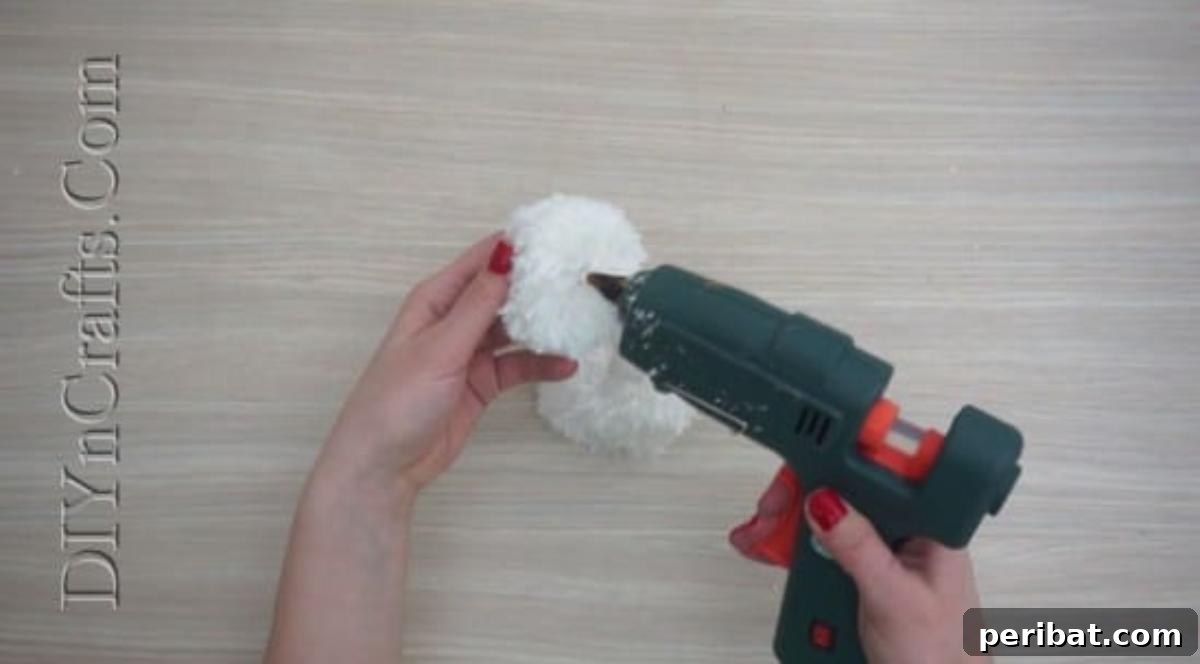 Snowman - Two white yarn pom-poms, one larger than the other, ready to be assembled as a snowman