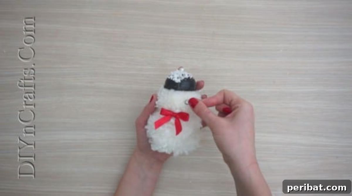 Snowman - The finished pom-pom snowman with its charming hat, eyes, and bow accessory