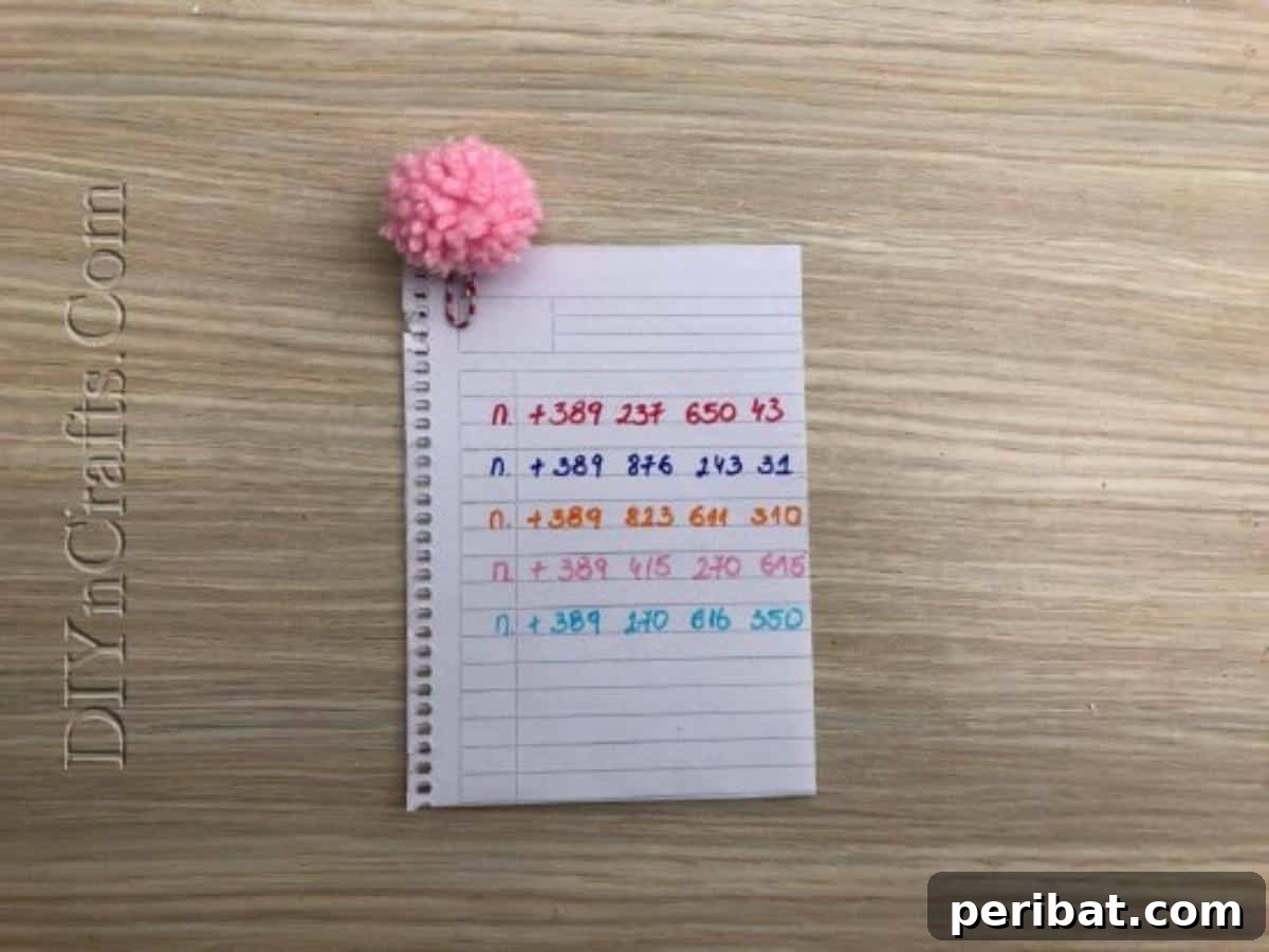 Bookmark - A finished pom-pom bookmark marking a page in a notebook for assignments
