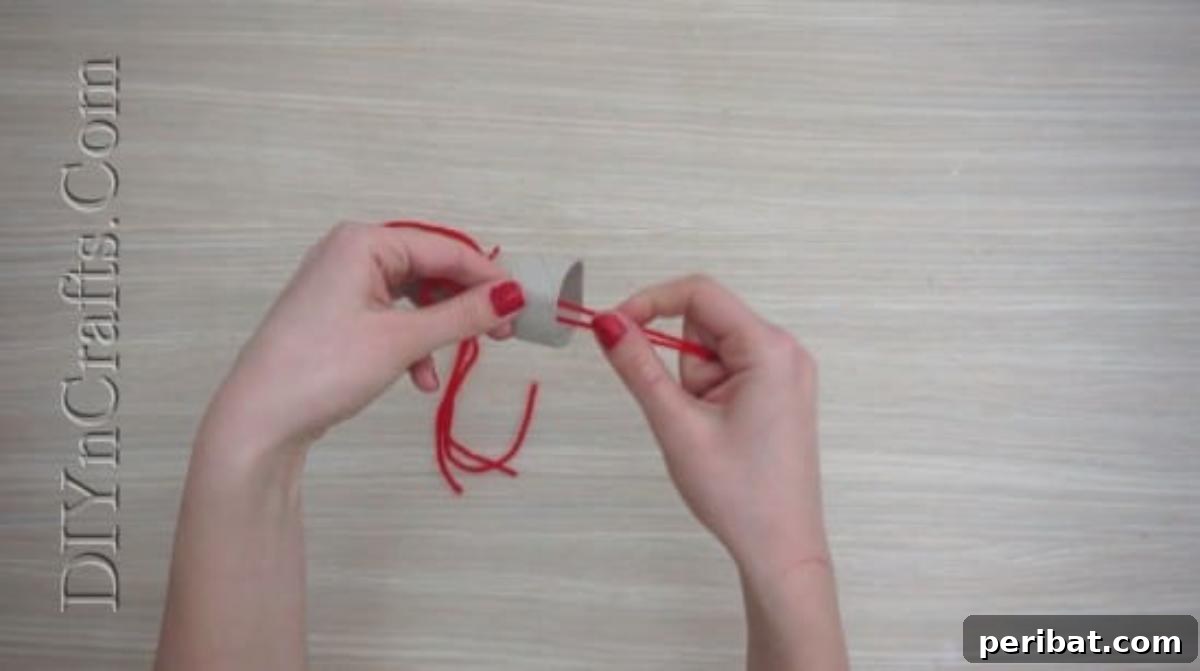 Hats - Forming a lark's head knot with yarn around a paper roll slice for a mini Christmas hat