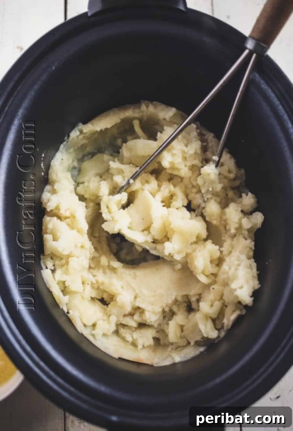 Mashing the cooked potatoes in the slow cooker