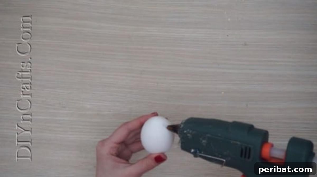 5 Brilliant & Easy Easter Egg Projects 11 Step 2: Attaching the first felt bunny ear to the top of an egg with hot glue, carefully positioning it for symmetry and stability.