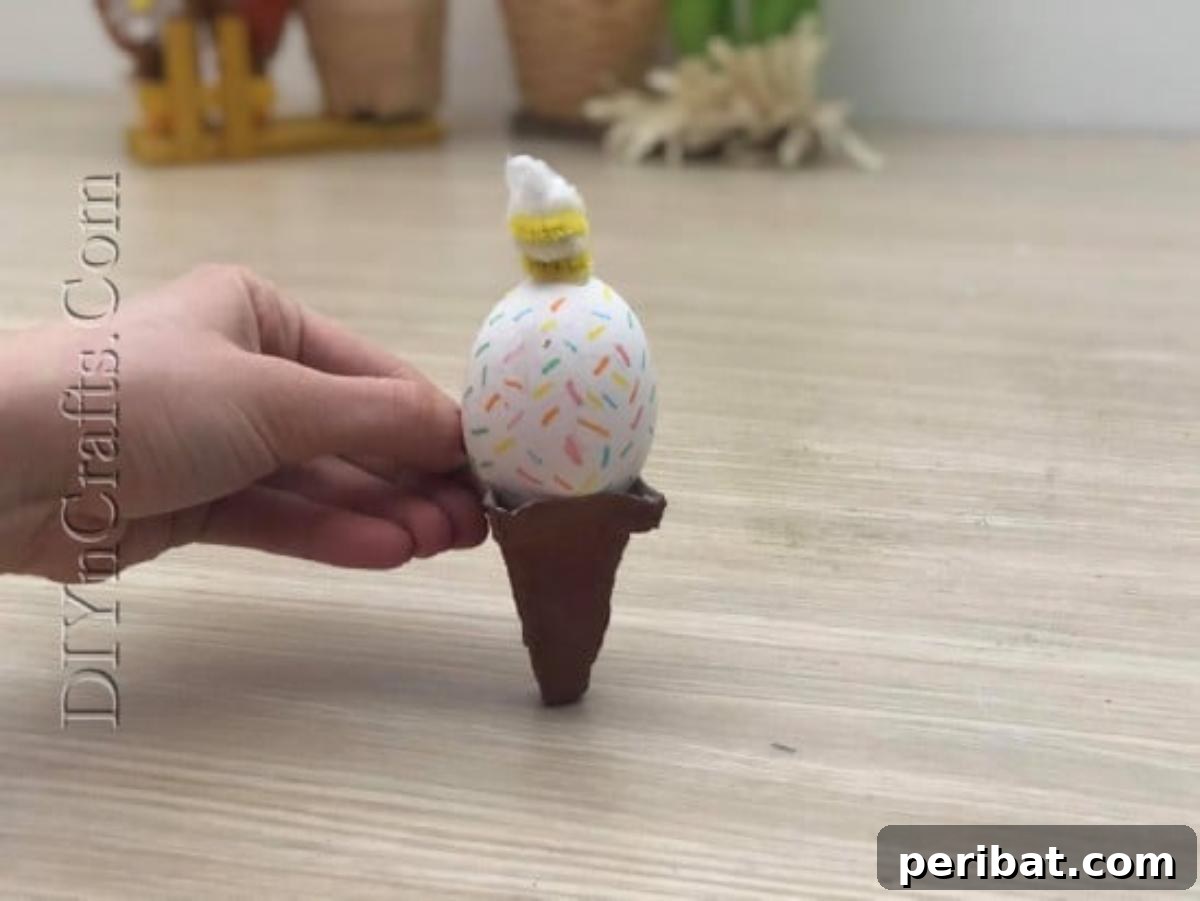 5 Brilliant & Easy Easter Egg Projects 6 The completed Ice Cream Cone Egg, nestled in a brown paper cone, showcasing its whimsical sprinkles, fluffy whipped topping, and pipe cleaner drizzle.