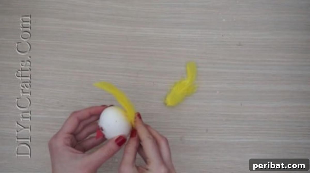 5 Brilliant & Easy Easter Egg Projects 9 Step 2: Attaching colorful craft feathers to the back of the egg with hot glue to form a vibrant, fanned-out tail for the bird decoration.