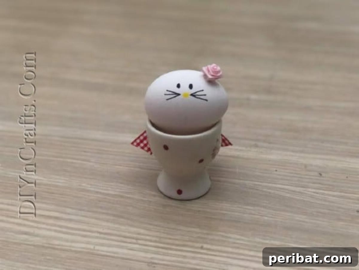 5 Delightful & Simple Easter Egg Crafts 11 A finished 'Kitty Egg' with a drawn face and a fabric flower, sitting cutely in an egg cup.