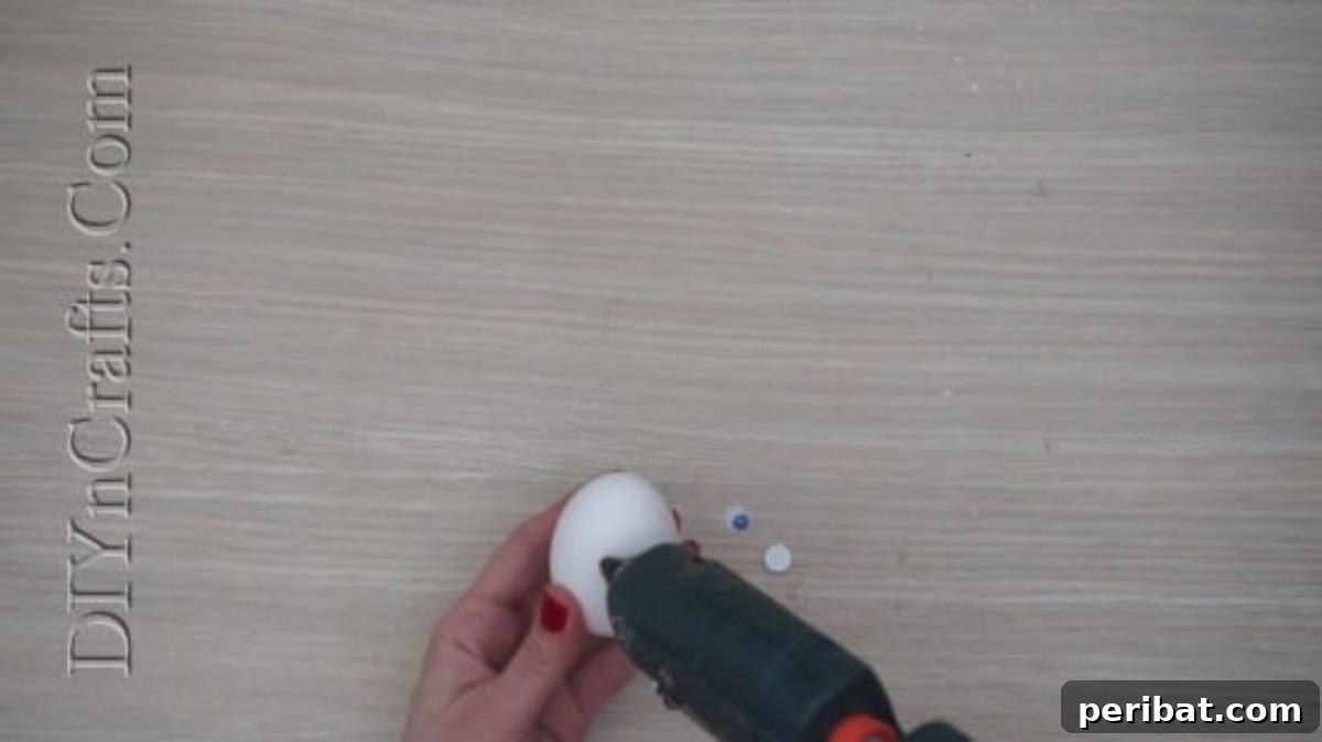 5 Delightful & Simple Easter Egg Crafts 17 Applying hot glue to the back of a googly eye before attaching it to an Easter egg.