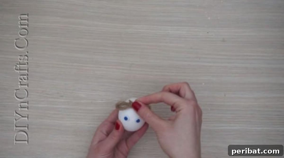 5 Delightful & Simple Easter Egg Crafts 19 A small twine bow being glued to the top of the Easter egg for the bunny's head decoration.