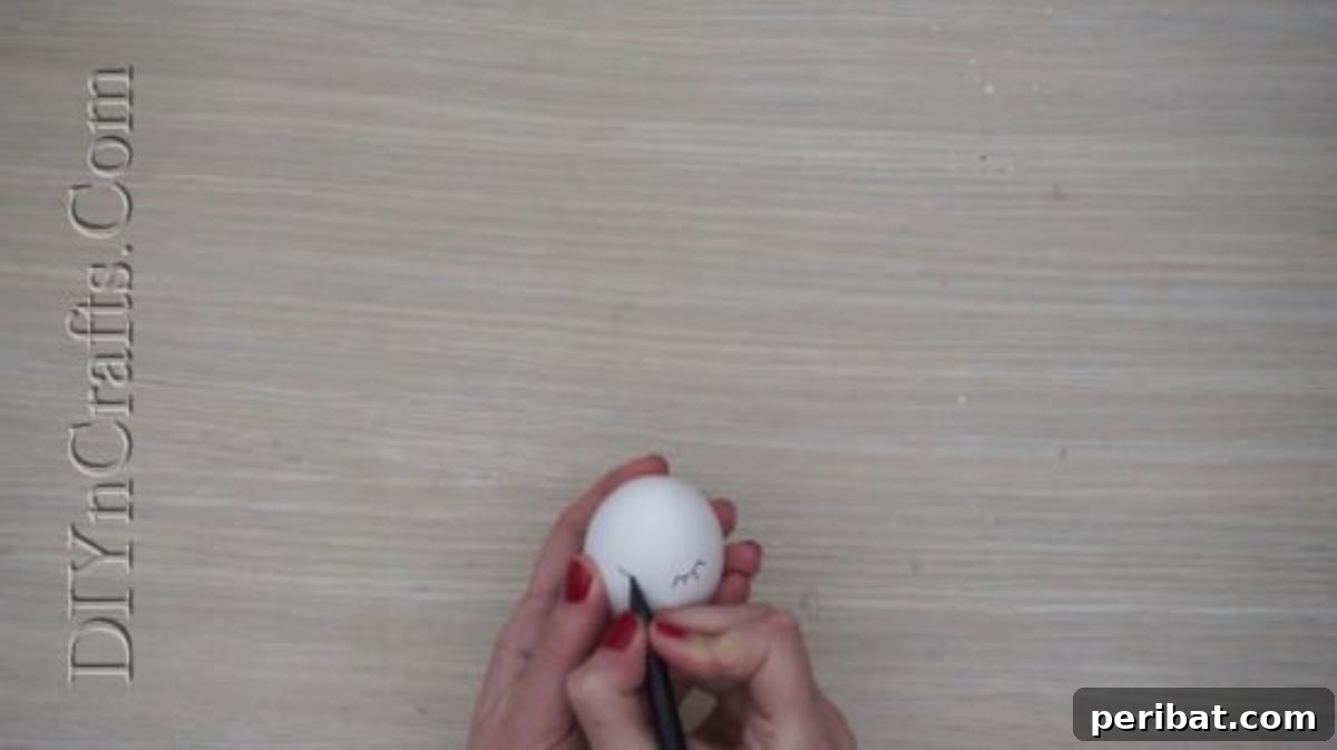 5 Delightful & Simple Easter Egg Crafts 3 Close-up of an Easter egg with a simple, pretty face drawn on it using a black pen.