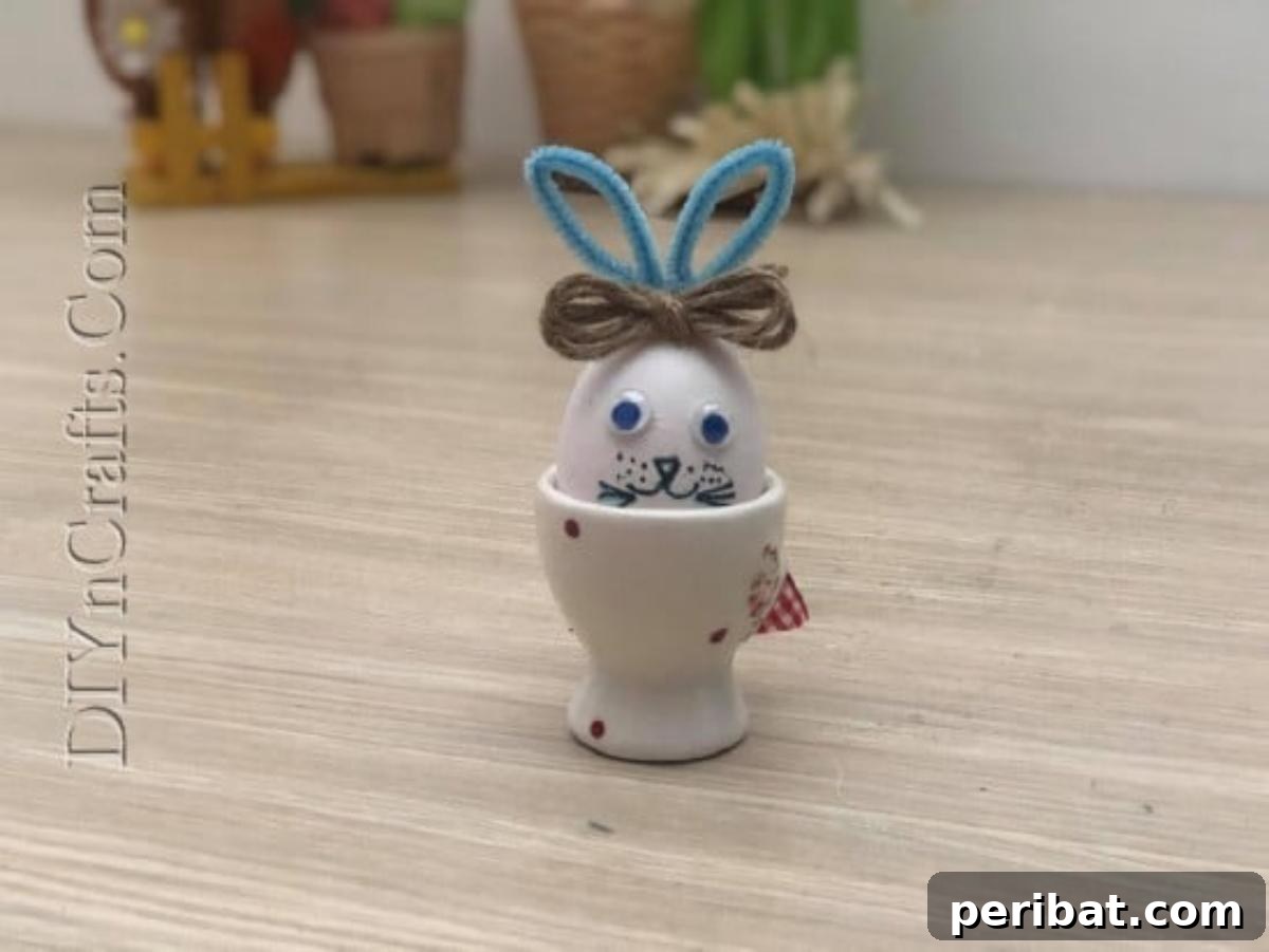 5 Delightful & Simple Easter Egg Crafts 22 A finished 'Bunny Egg' with googly eyes, pipe cleaner ears, a twine bow, and drawn features, sitting in an egg cup.