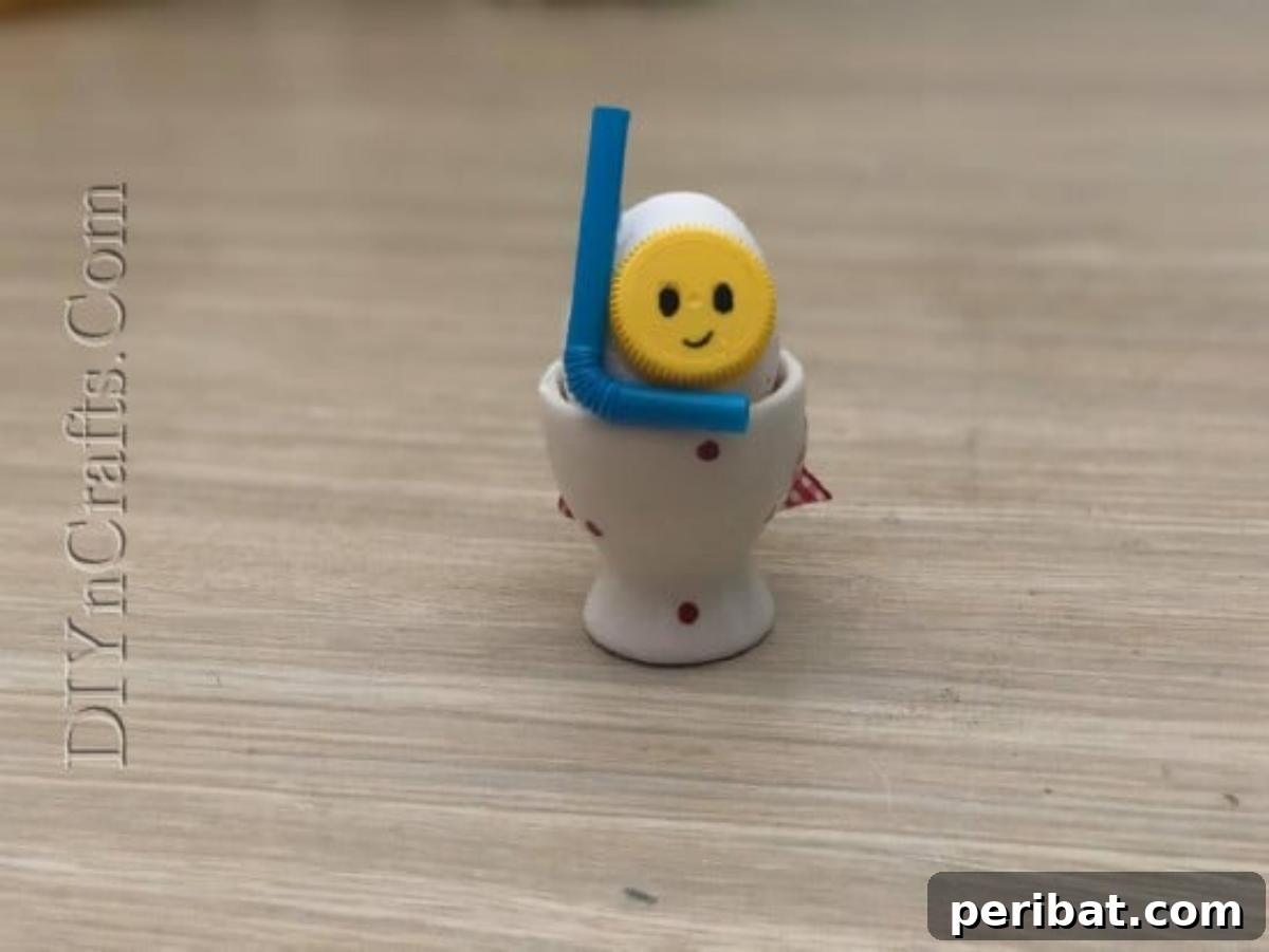 5 Delightful & Simple Easter Egg Crafts 27 A finished 'Snorkeling Egg' with a bottle cap mask, drawn face, and bendy straw snorkel, displayed in an egg cup.