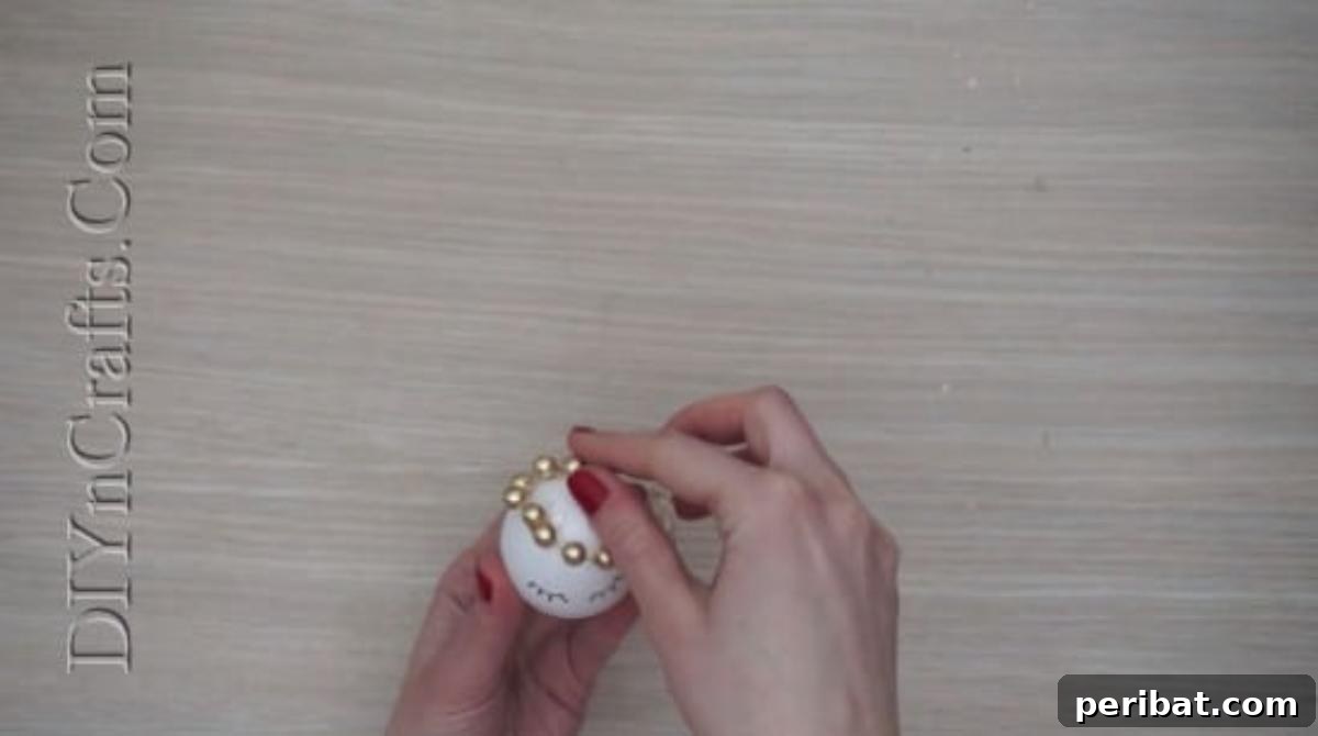 5 Delightful & Simple Easter Egg Crafts 5 A delicate beaded string being affixed to the top of an Easter egg to form a crown.