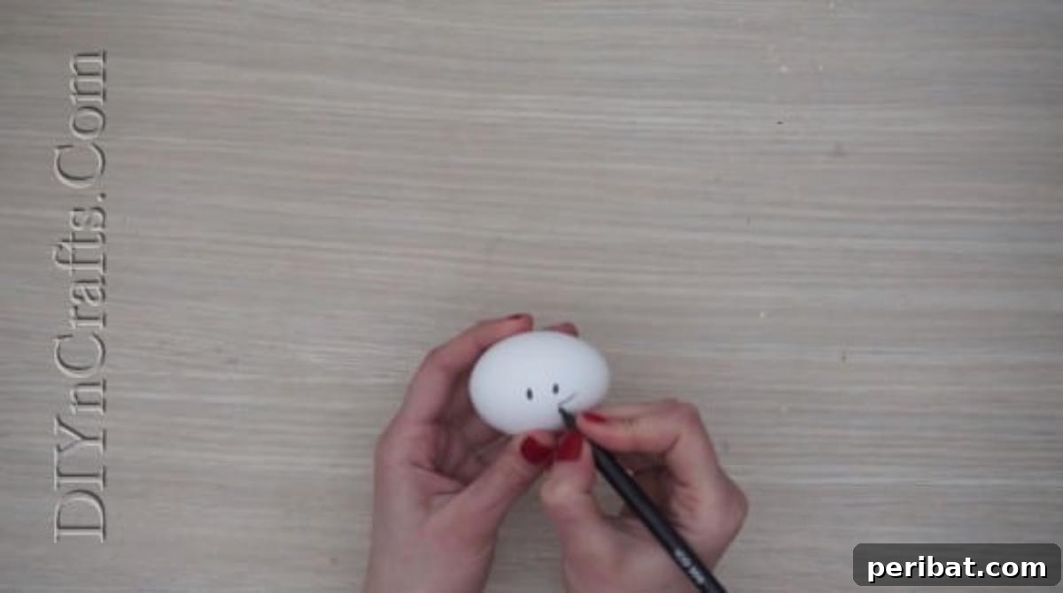 5 Delightful & Simple Easter Egg Crafts 7 An Easter egg held sideways, with a cute kitty face being drawn on it using a black pen.