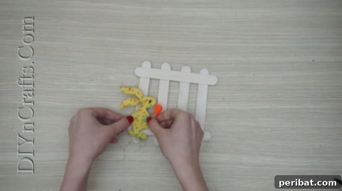 Craft Stick Easter Magic: 5 Simple DIY Projects 13 Gluing an Easter bunny embellishment onto the craft stick fence