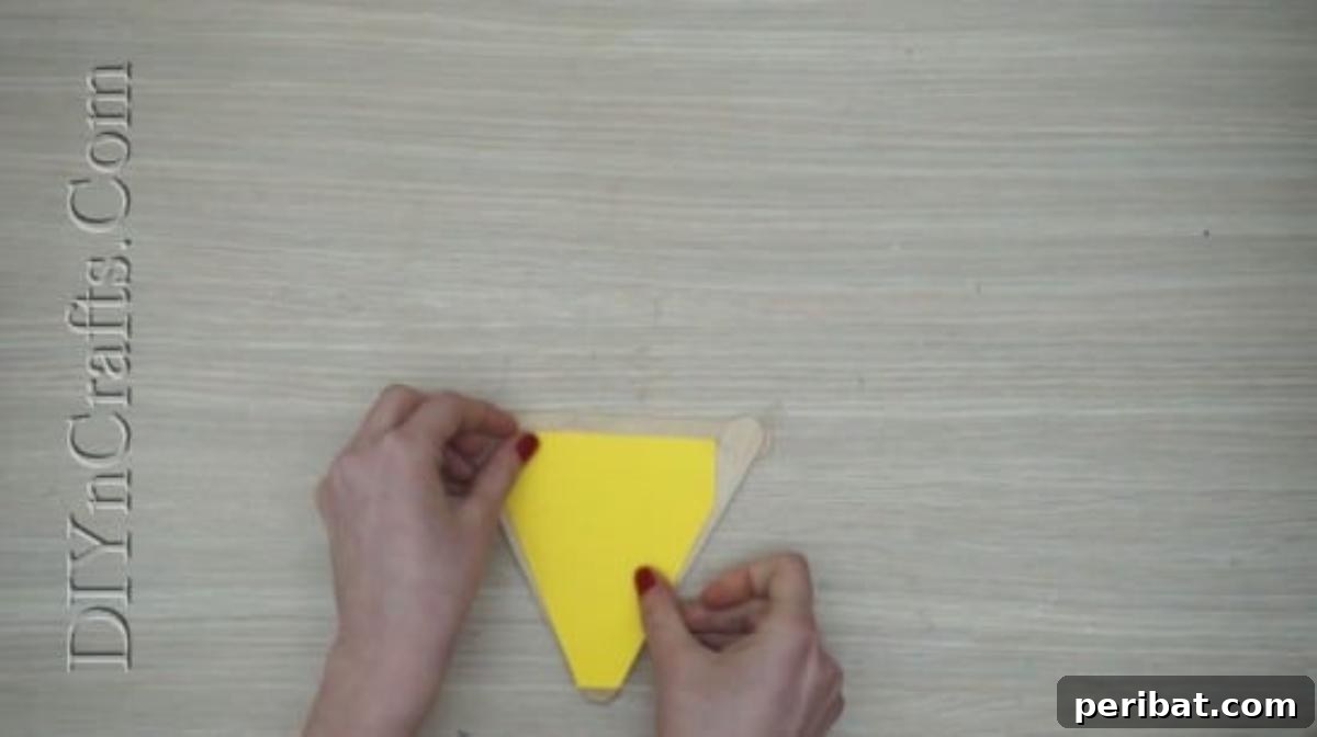 Craft Stick Easter Magic: 5 Simple DIY Projects 25 Yellow construction paper triangle glued inside the craft stick frame for the chick's body