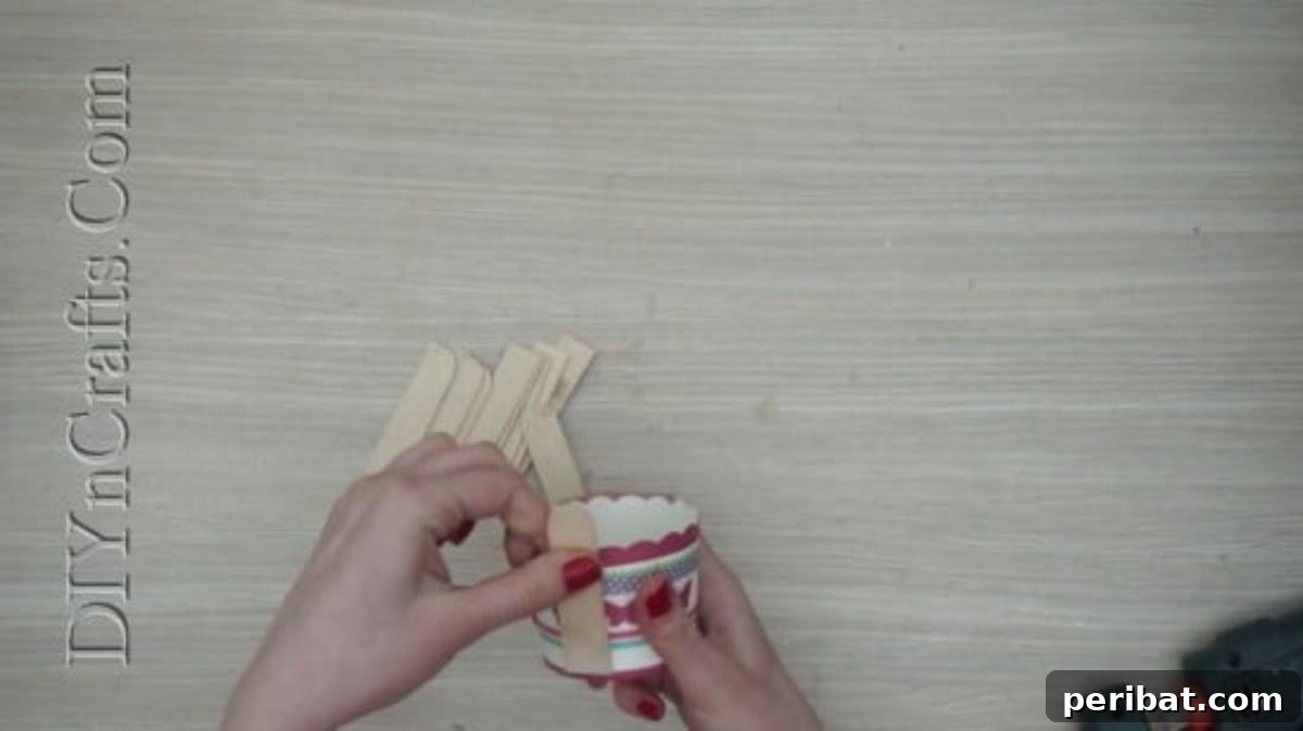 Craft Stick Easter Magic: 5 Simple DIY Projects 31 Attaching the first craft stick to the side of a small cup for the Easter basket