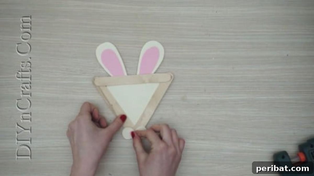 Craft Stick Easter Magic: 5 Simple DIY Projects 6 White circles and a pink nose shape glued onto the bunny's face