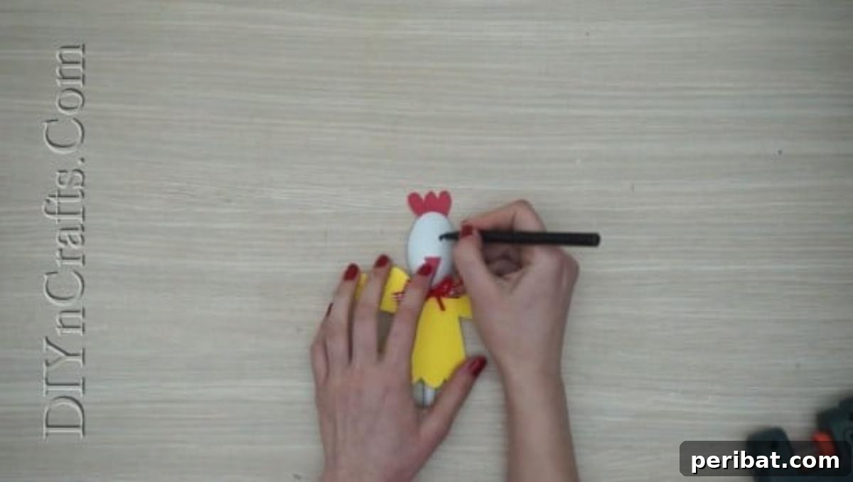 Spoonfuls of Fun 5 Easter Crafts for Kids Using Plastic Spoons 17 A black marker is used to draw eyes onto the plastic spoon chick, which has a red comb and beak already attached.