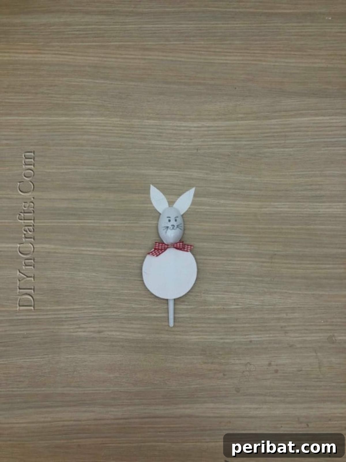 Spoonfuls of Fun 5 Easter Crafts for Kids Using Plastic Spoons 24 The finished Bunny Spoon 2 craft, showcasing a plastic spoon with a white paper round body, white paper ears, a bow, and a hand-drawn bunny face.