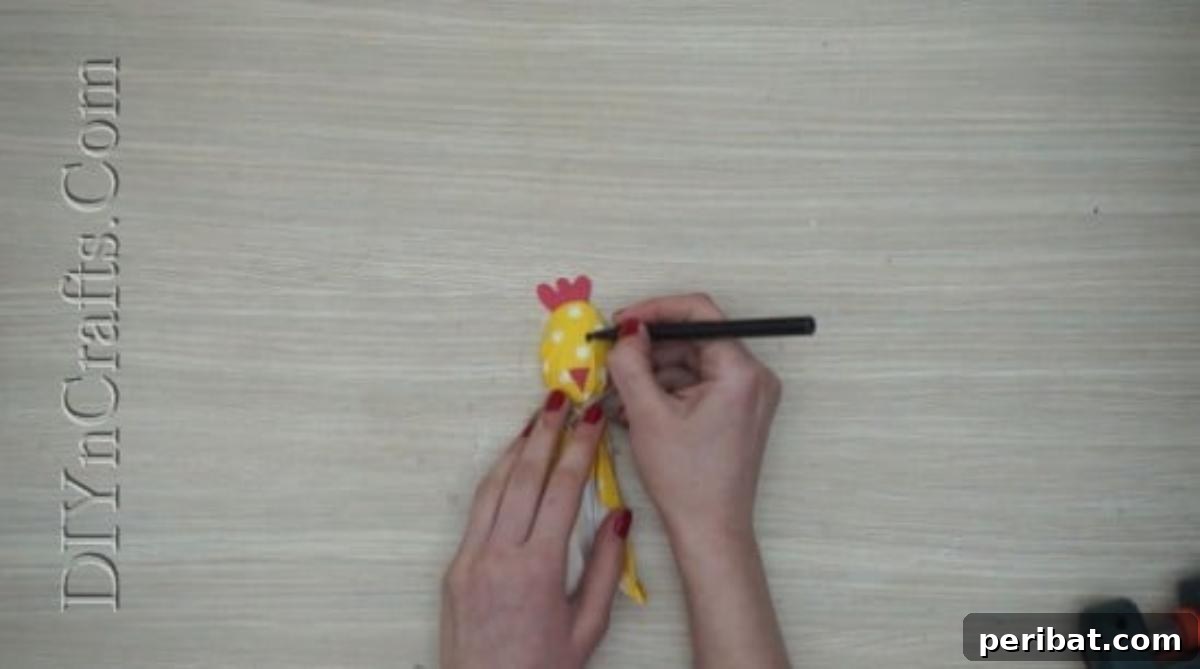 Spoonfuls of Fun 5 Easter Crafts for Kids Using Plastic Spoons 28 A black marker is used to draw eyes on the tissue-paper-covered plastic spoon chick, which has a red comb and beak.