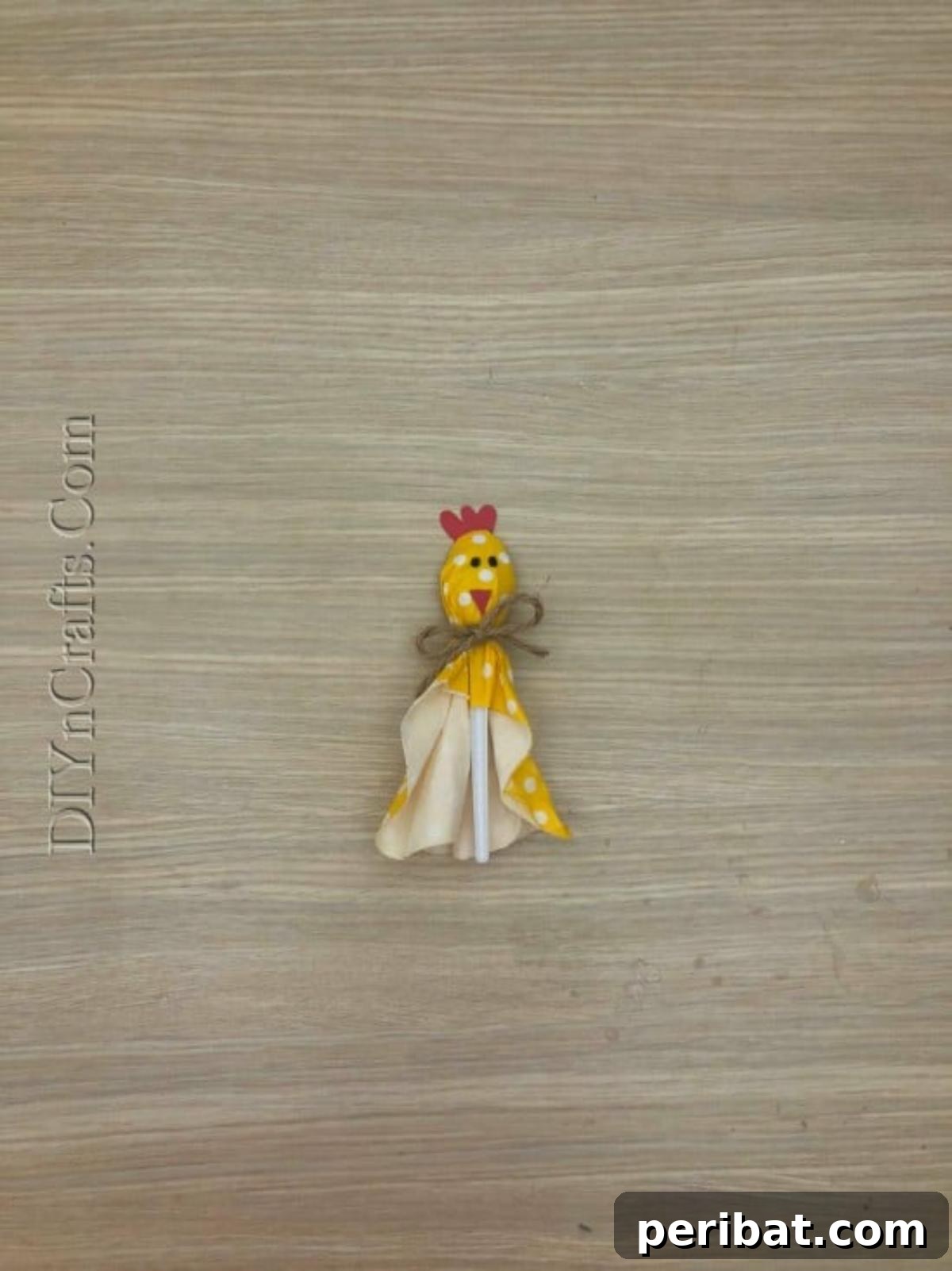 Spoonfuls of Fun 5 Easter Crafts for Kids Using Plastic Spoons 29 The completed Fluffy Tissue Paper Chick Spoon craft, showing a plastic spoon wrapped in yellow polka-dotted tissue paper, tied with twine, and decorated with a red comb, beak, and drawn eyes.