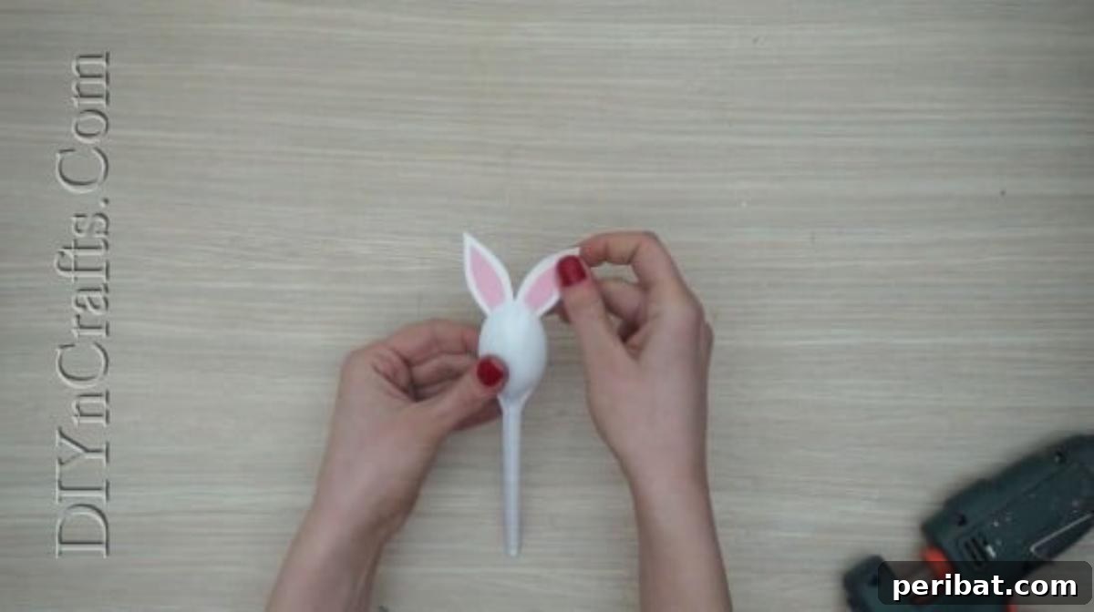 Spoonfuls of Fun 5 Easter Crafts for Kids Using Plastic Spoons 5 The white plastic spoon now has two paper bunny ears firmly attached to its back, forming the basic head shape.