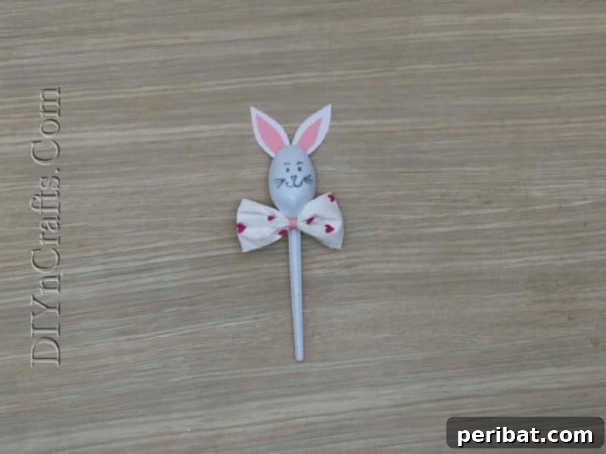 Spoonfuls of Fun 5 Easter Crafts for Kids Using Plastic Spoons 8 The completed Bunny Spoon 1 craft, featuring a plastic spoon with paper ears, a pink bow tie, and a hand-drawn bunny face.
