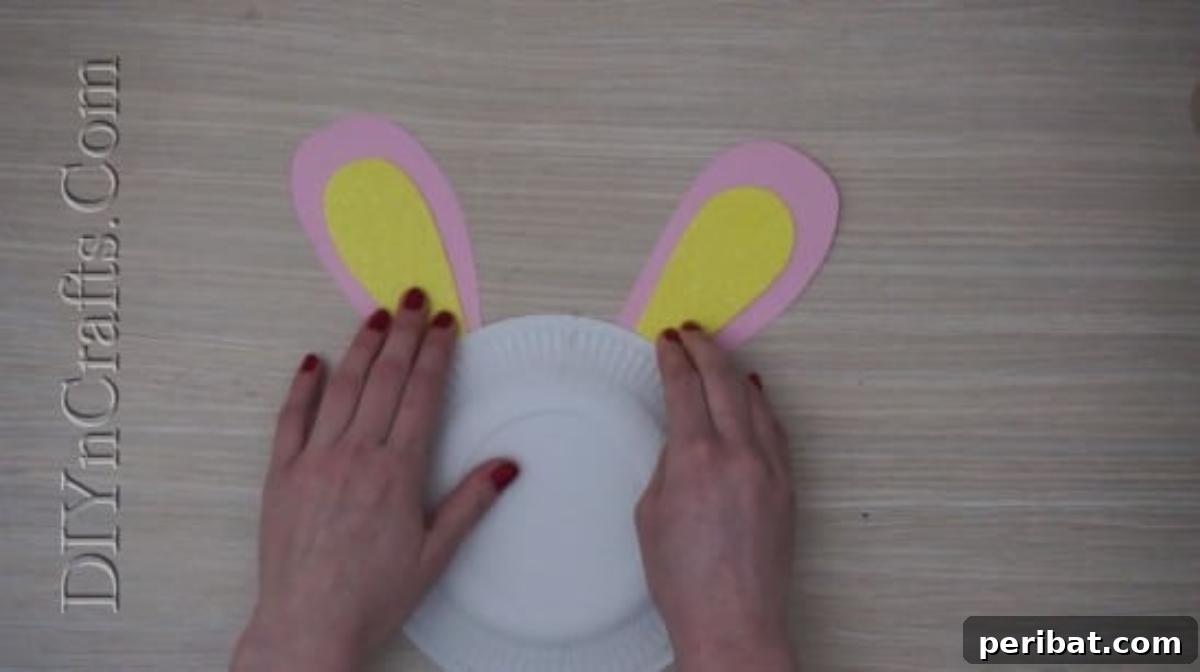 Instant Easter Fun: 5 Crafts for Kids in Under 5 Minutes 5 Securing the bunny ears firmly onto the paper plate, forming the basic head shape.