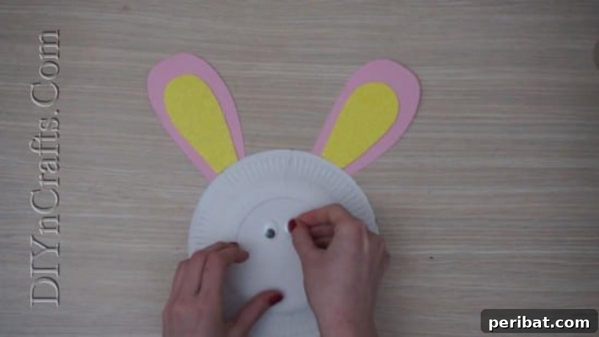Instant Easter Fun: 5 Crafts for Kids in Under 5 Minutes 6 Attaching googly eyes to the paper plate bunny face, bringing the craft to life.
