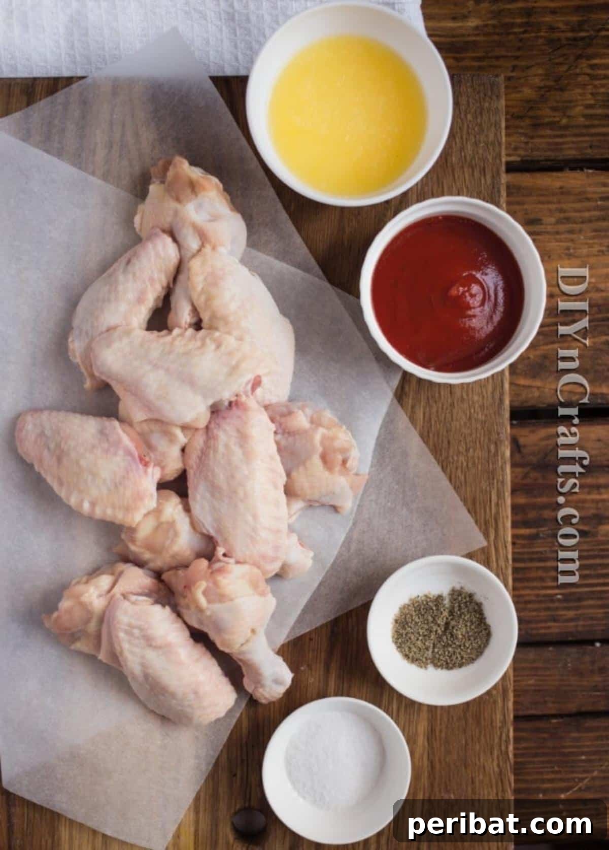 Fresh chicken wings, butter, hot sauce, and vegetable oil laid out on a kitchen counter, ready for preparation.