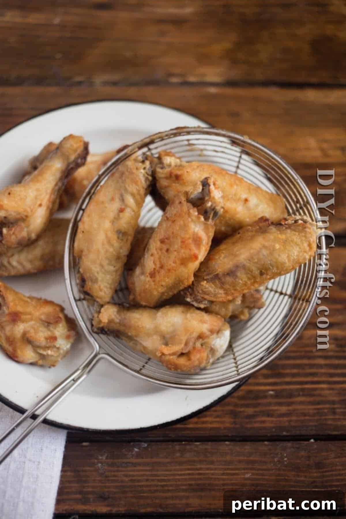 Golden-brown chicken wings being removed from hot oil after their second, high-temperature fry, showcasing their incredible crispiness.