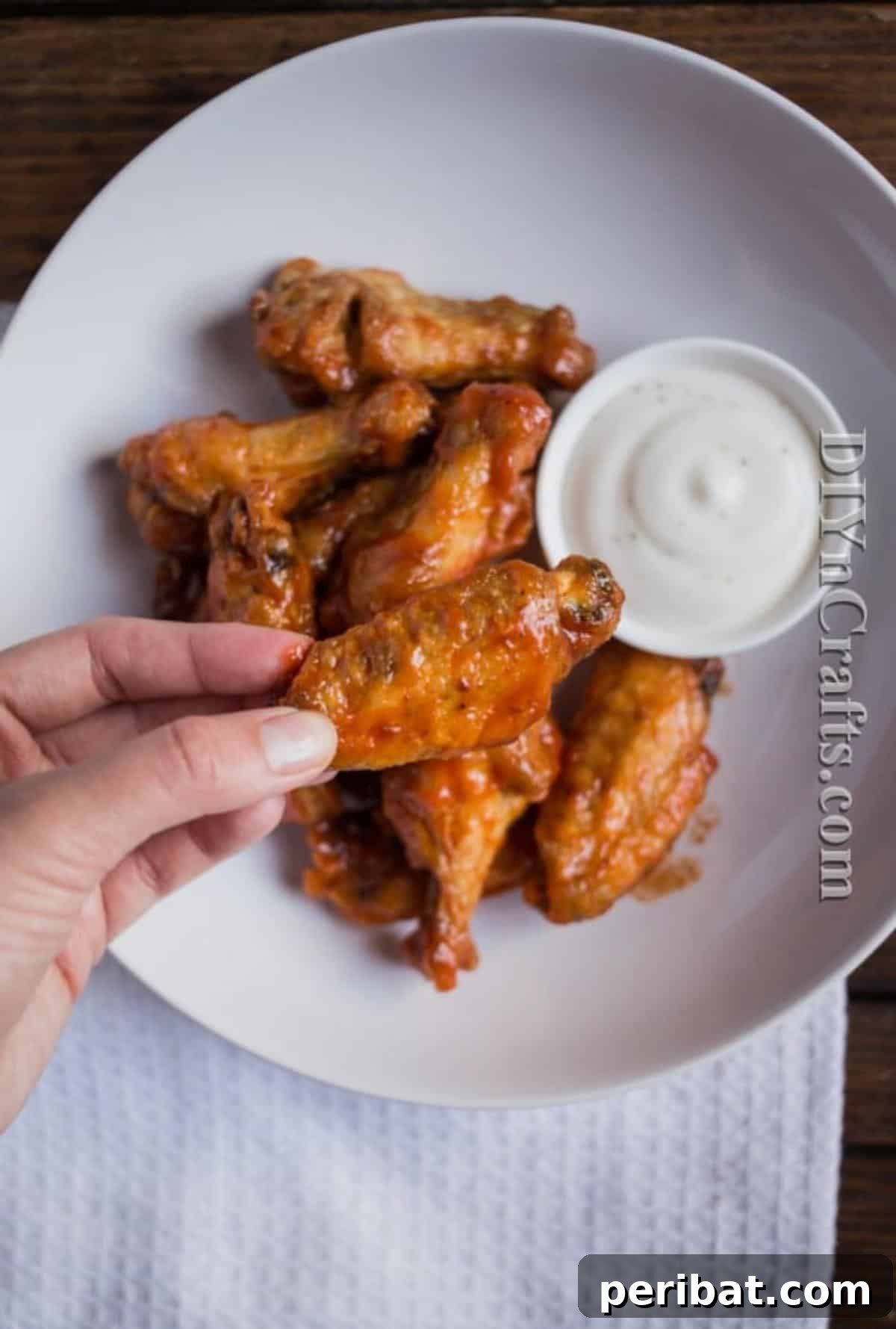 A bowl of freshly sauced, extra crispy double fried confit buffalo wings garnished with parsley, ready to be enjoyed.