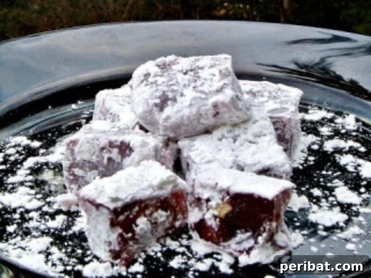 Homemade pomegranate Turkish Delight cubes dusted with powdered sugar and chopped walnuts.