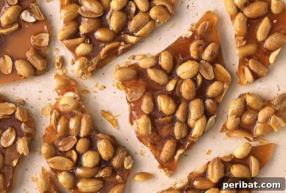Cracked pieces of classic homemade peanut brittle with visible peanuts.
