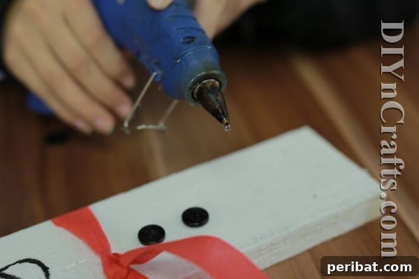 Craft Your Own Rustic Christmas Snowman 14 Gluing buttons onto the rustic snowman