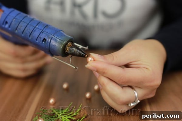 Infuse Your Tree with Rustic Aroma: DIY Ornaments 8 Applying faux pearls to the pine sprigs with hot glue as miniature Christmas tree ornaments.